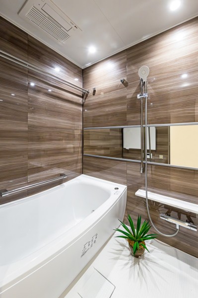 光沢のある木目調パネルが高級感を漂わせるバスルームです。ワイドミラーによって実際より色く感じられるくつろぎの空間です。
