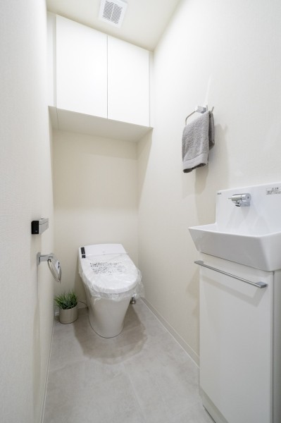 お掃除の手間を減らしてくれる機能が充実したトイレです。備え付けの吊戸棚は、トイレットペーパーや清掃用具などが収納できて便利です。