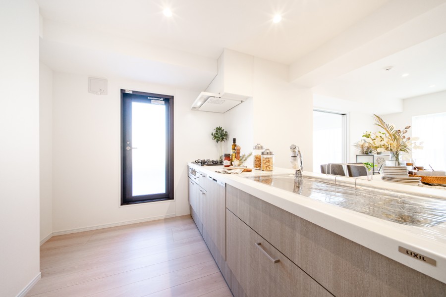 キッチン横にはルーフバルコニーへ続く扉があるので、換気がしやすいスペースです。ホワイトの美しい天板や温もりある木目調の美しいデザインが特長のオープンキッチンです。