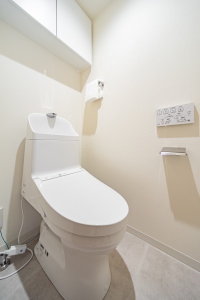 TOTO製ウォシュレット一体型のトイレは、お掃除の手助けをしてくれる便利機能が搭載されています。上部には収納に便利な吊戸棚を備え付けました。