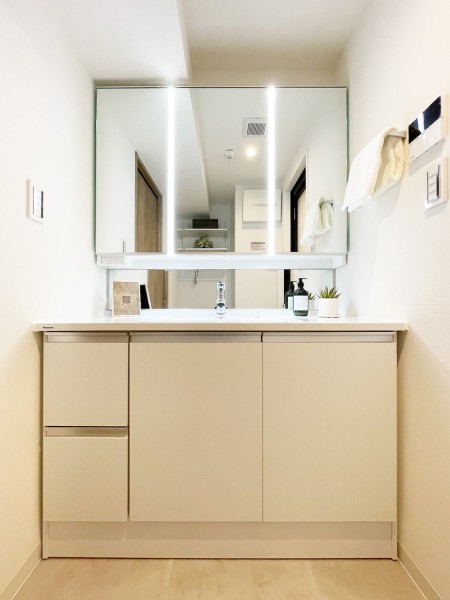 白を基調とした清潔感溢れるデザインの洗面化粧台です。三面鏡の裏側や足元のキャビネットなど、収納豊富で実用的な洗面空間です。