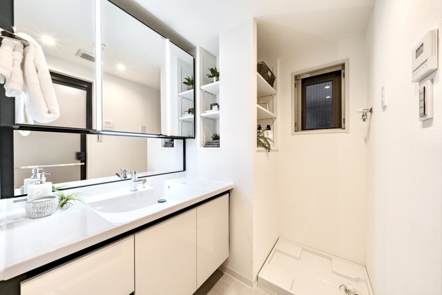 白を基調とした清潔感溢れるデザインの洗面化粧台です。三面鏡の裏側や足元のキャビネットなど、収納豊富で実用的な洗面空間です。