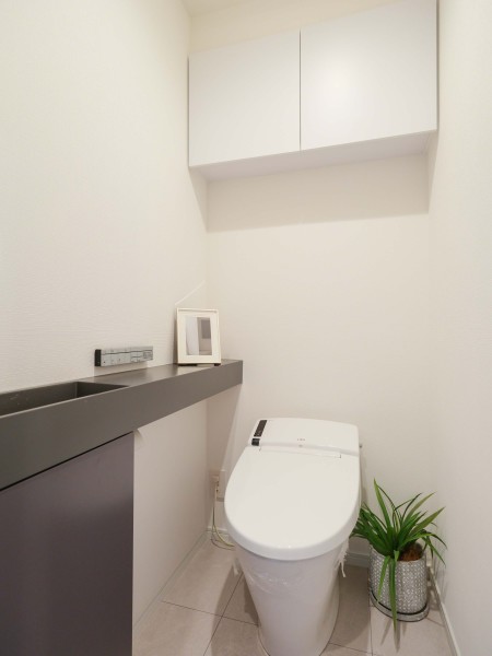ウォシュレット一体型のトイレは、お掃除の手助けをしてくれる便利機能が搭載されています。上部には収納に便利な吊戸棚を備え付けました。