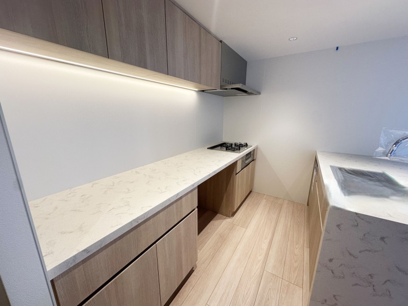 美しい木目の面材はインテリアの一部のようでお部屋の雰囲気に溶け込みます。Ⅱ列型キッチンなので、作業スペースが広くゆとりのある「居心地」も良いスペースです。