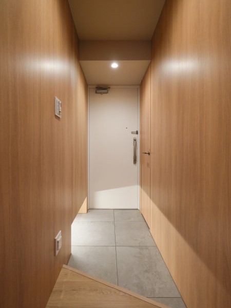玄関の框を斜めにデザインすることで空間を広く見せる設計を施しました。住戸へ入室した瞬間に胸が躍る、お部屋の顔となる玄関。ウッド調の建具に包まれた心安らぐ住まいです。