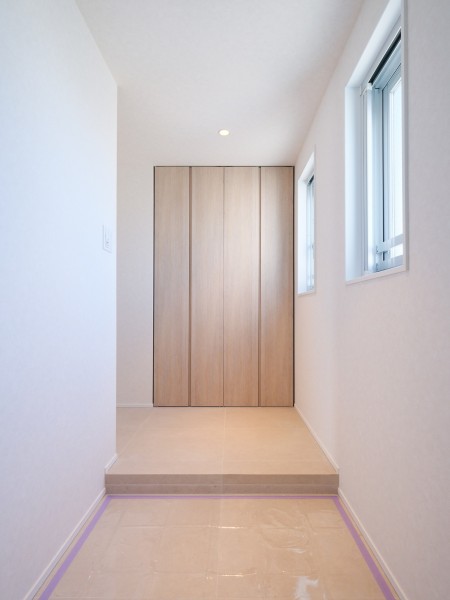 扉を開けた瞬間に広がるのは、明るく清々しい玄関スペースです。小窓から差し込む光が、温かみのある木目調の建具と美しく調和し、住まう方を優しく迎え入れます。