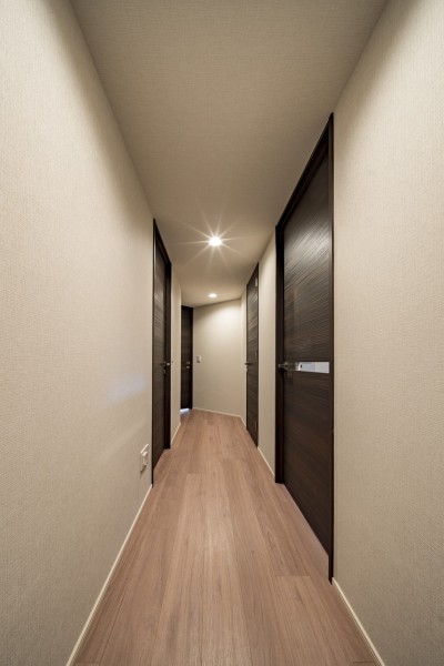 お部屋に続く廊下は、ドラマティックな住空間を引き締めるダークカラーの建具がアクセントになっています。天井まで続くフルハイトドアが品格を醸し出します。