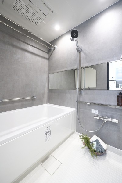落ち着いたグレーの壁面が上品な雰囲気を演出するバスルームです。横長ミラーの効果で実際のサイズよりも広がりを感じられます。