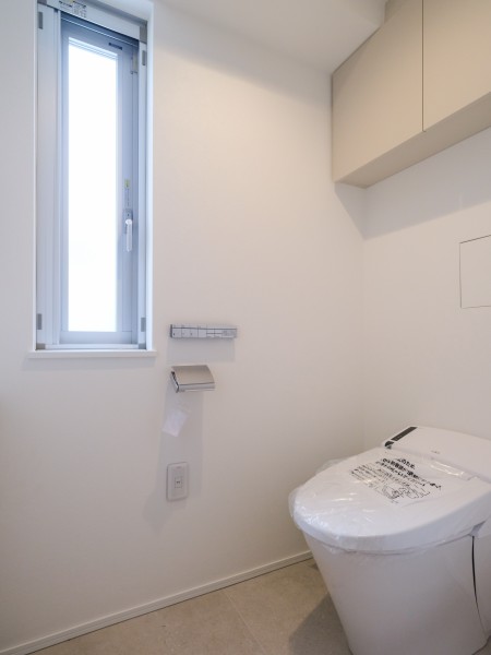 タンクレストイレやスティックリモコンでスタイリッシュな空間を演出します。トイレットペーパーなどの収納に便利な吊戸棚を備え付けました。