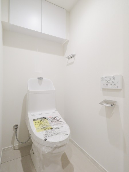 シンプルで安らぎが宿るレストルームです。ウォシュレット一体型のトイレは、お掃除の手助けをしてくれる便利機能が搭載されています。トイレットペーパーなどの収納に便利な吊戸棚を備え付けました。