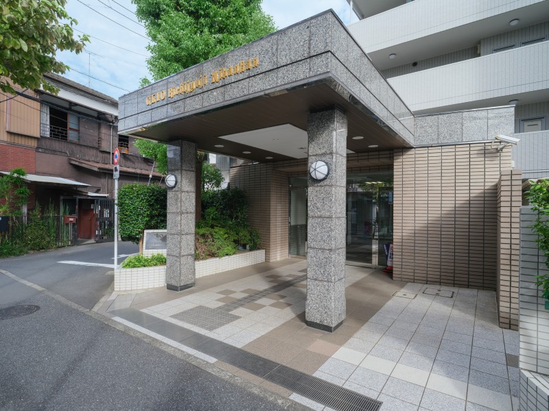 御影石調の柱や庇が存在感を演出するエントランスです。植栽が配されたアプローチとあわせて、落ち着いた雰囲気の共用空間が広がっています。
