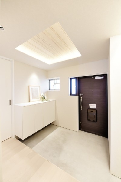 玄関から住まいのコンセプトを感じられる設計。無垢突板材をあしらった折り上げ天井と間接照明が奥行きを演出し、住戸の奥へと自然に視線を導きます。上質な素材感と開放感が調和した、印象的なエントランス空間です。